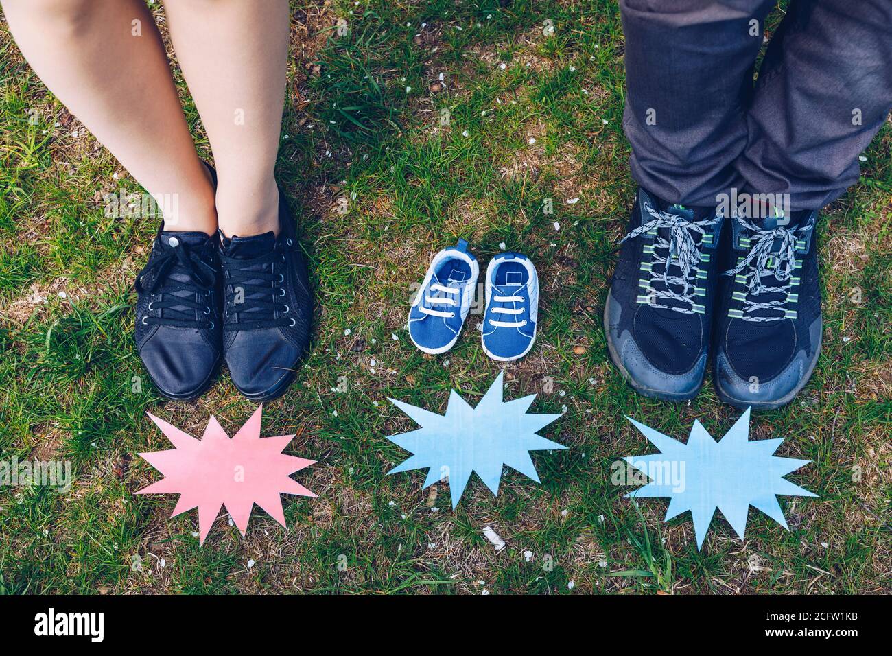 Young couple waiting for baby. Expecting parents with little baby boy shoes. Concept of Parents-To-Be. Shoes and sneakers of parents and expected baby Stock Photo