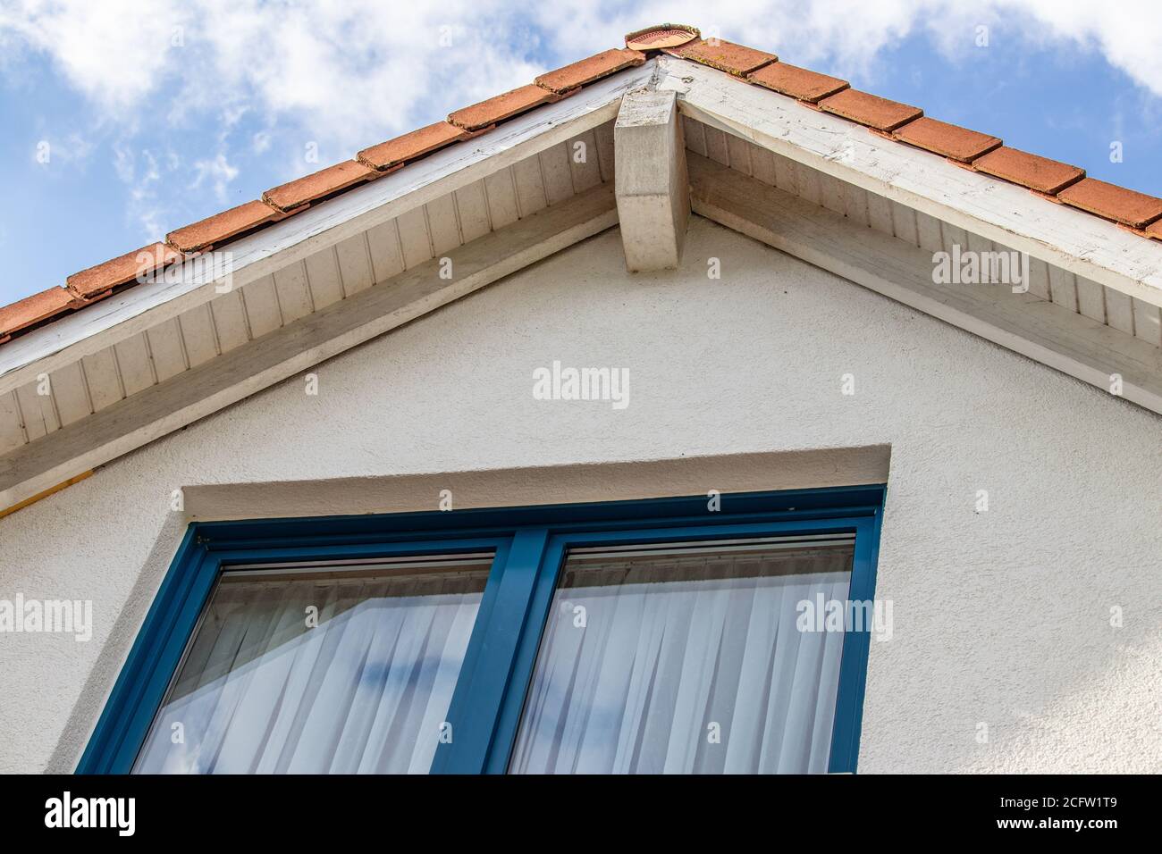 Low angle shot of a house roof with a blue window Stock Photo