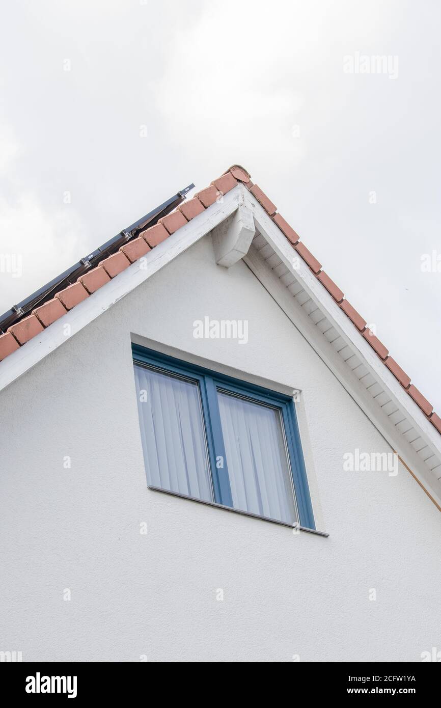 Vertical closeup shot of a housetop with a blue window Stock Photo