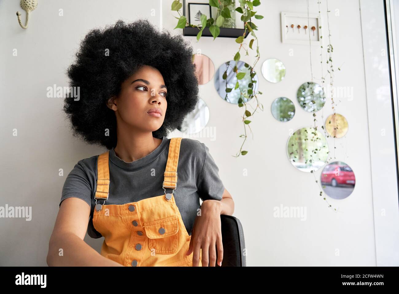 Thoughtful pensive African lady looking through window sitting at home, in cafe. Stock Photo