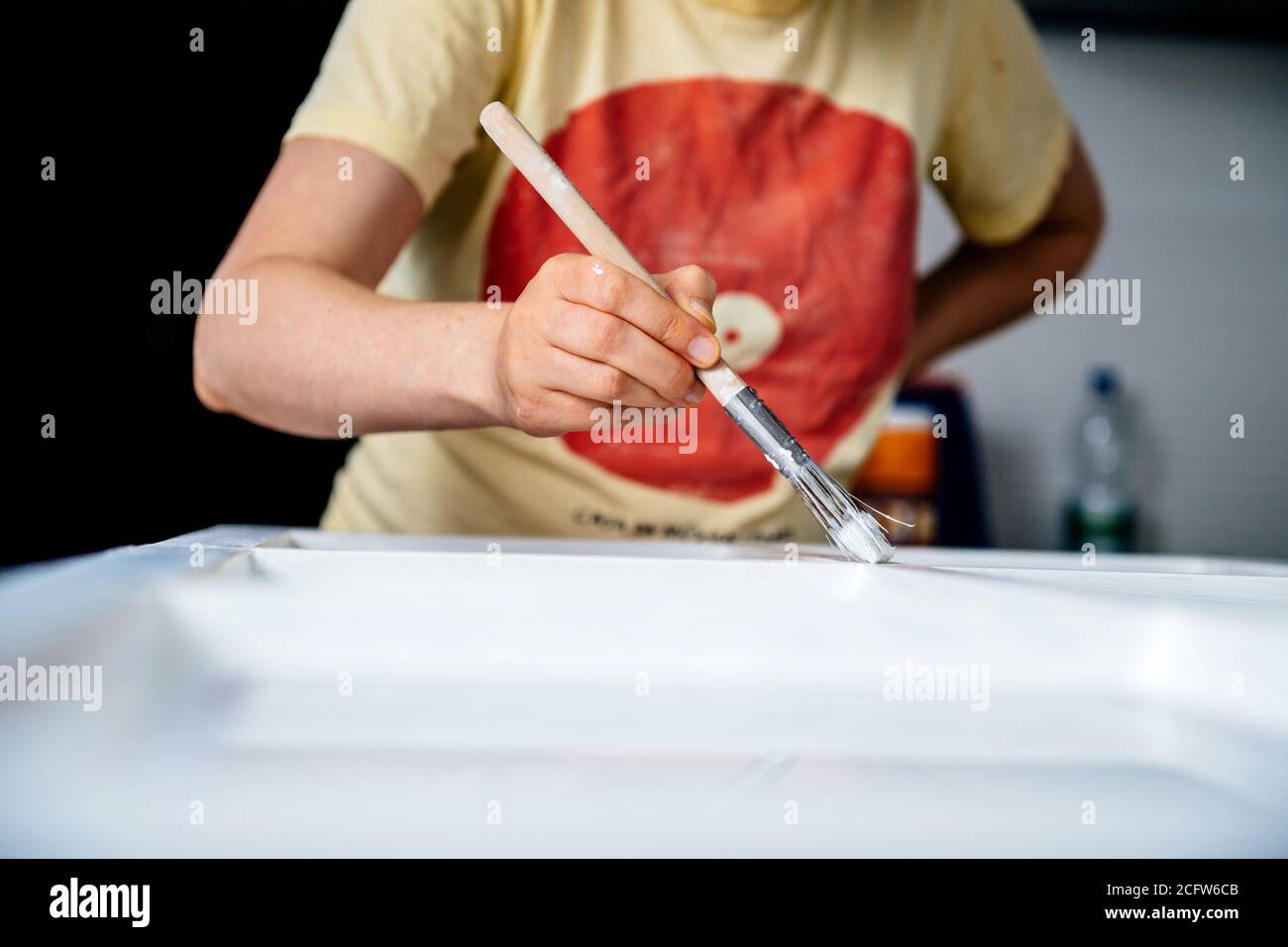 Focus on the hand of pregnant woman doing painter job renovation of old wooden window frame