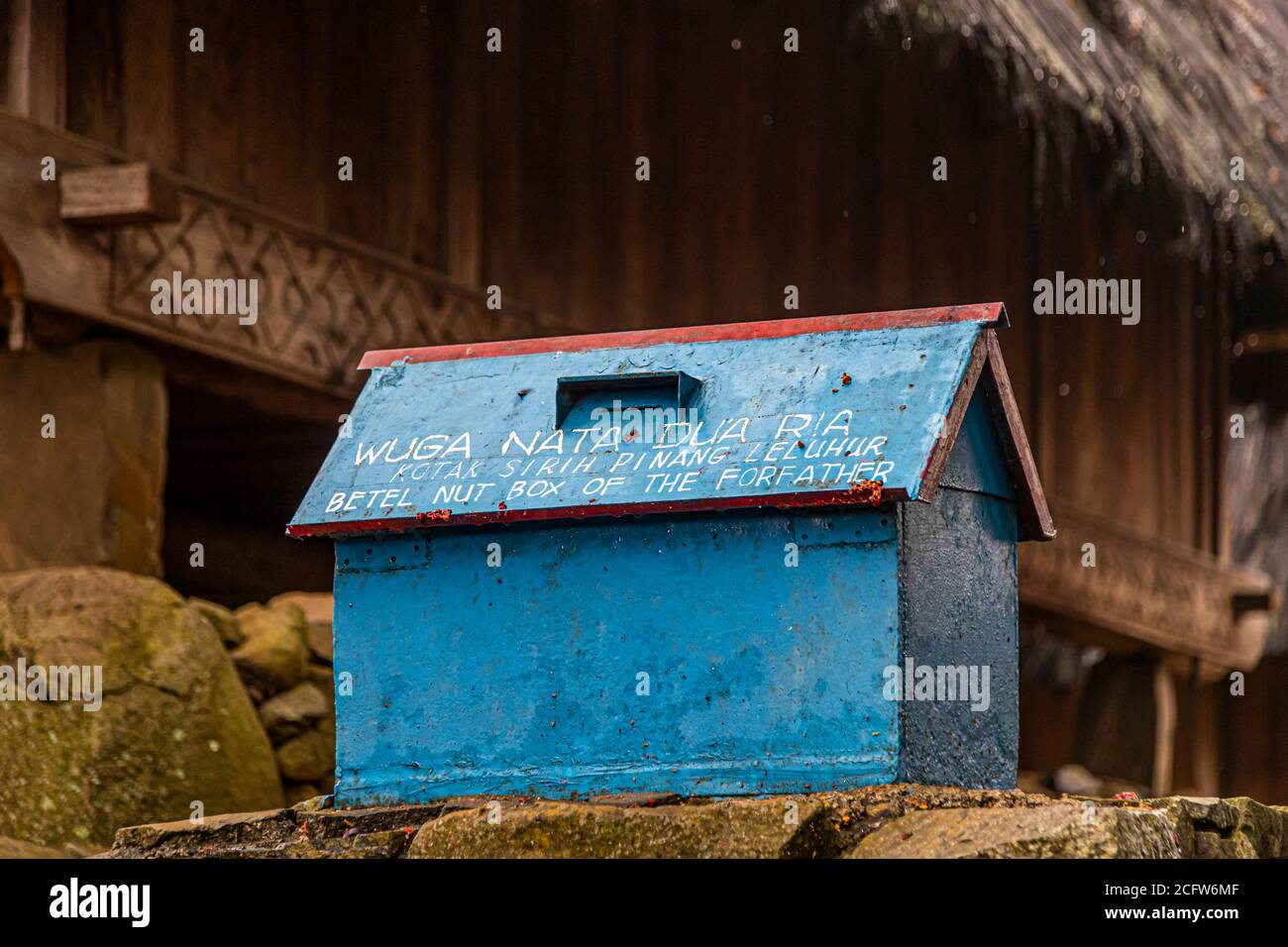 A blue-painted wooden box labelled "Wuga Nata Dua Ria – Betel Nut Box of the Forfather" serves as a ceremonial container for the ancestors' betel nuts in a mountain village near Moni, Flores, Indonesia. Stock Photo