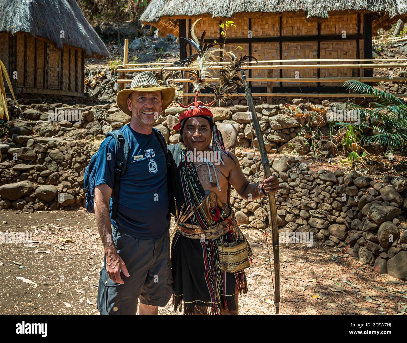 Photographer Georg Berg poses for a photo with a dancer in traditional dress and feathered headdress in the village of Takpala, Alor, Indonesia. Stock Photo