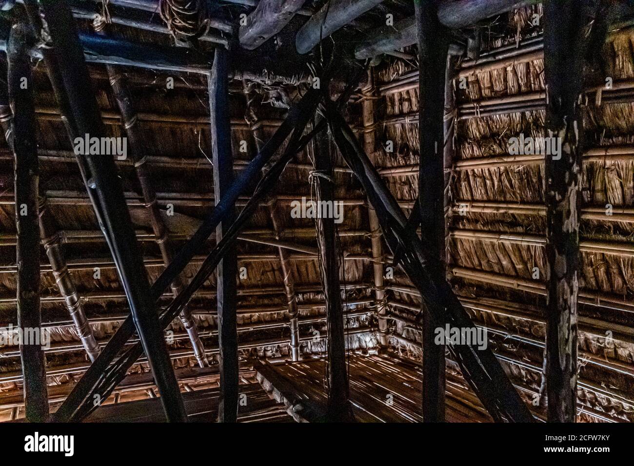 Bamboo struts and woven thatch form the roof structure inside a traditional grain barn known as a lumbung on Alor, Indonesia. Stock Photo