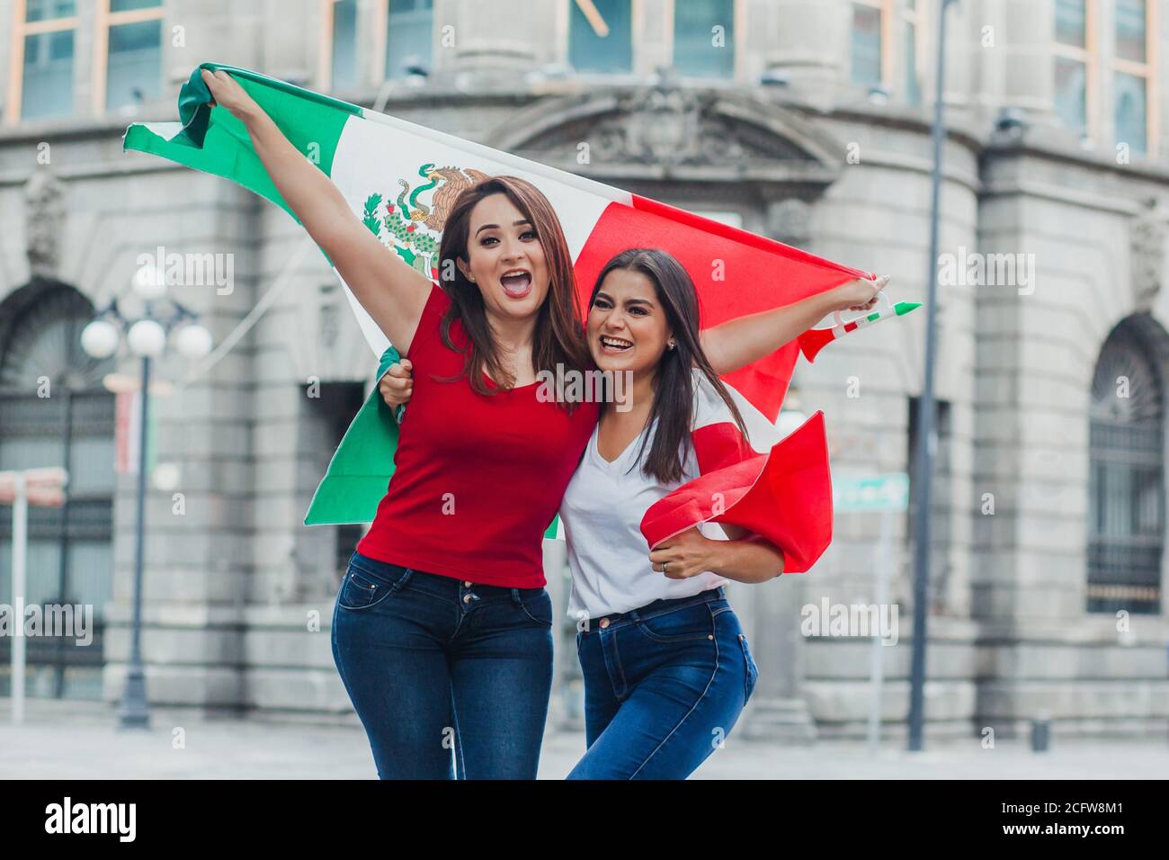 mexican girls friends at independence day in Mexico holding a flag of mexico Stock Photo
