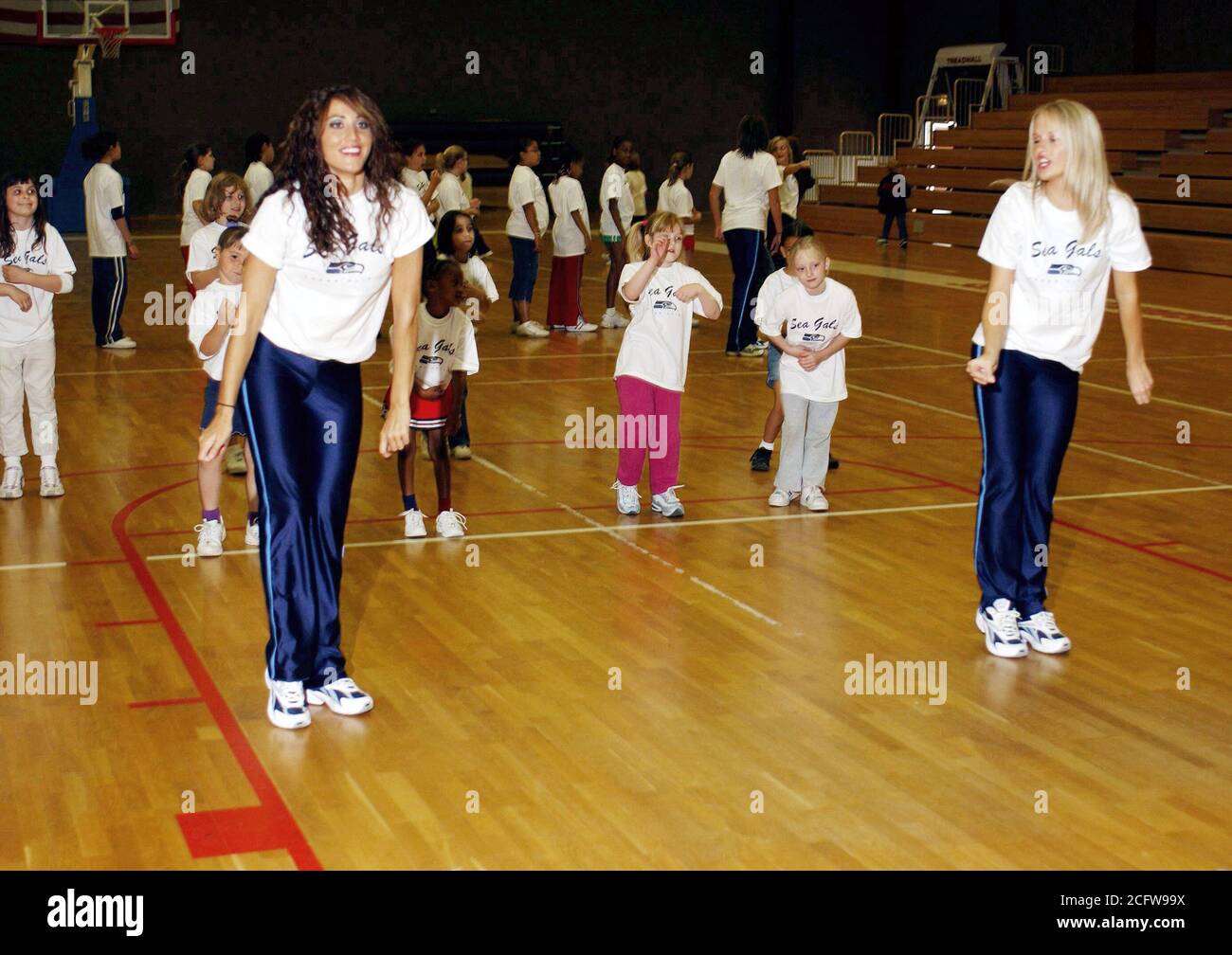 Niesha Thompson (foreground left) and Allison Kalkoske, both with the National Football League (NFL) Seattle Seahawks, Sea Gals Cheerleaders, teach a dance routine to girls from Spangdahlem Air Base (AB), Germany. Stock Photo