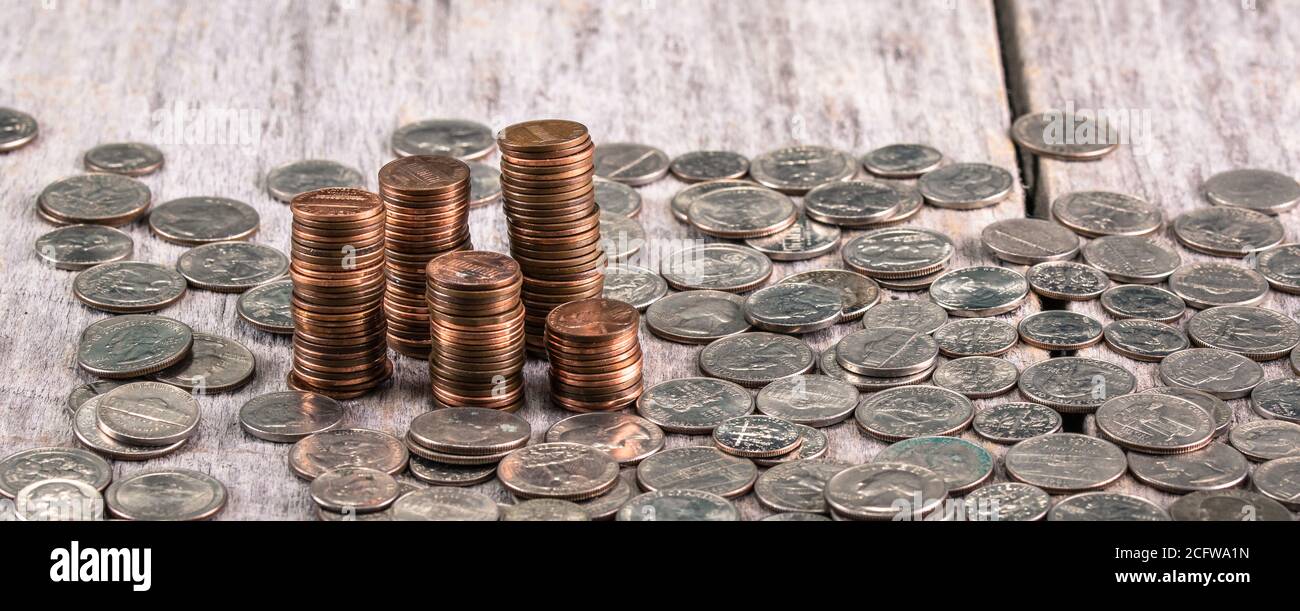 Stacks of old pennies on a wooden table amongst other coins Stock Photo
