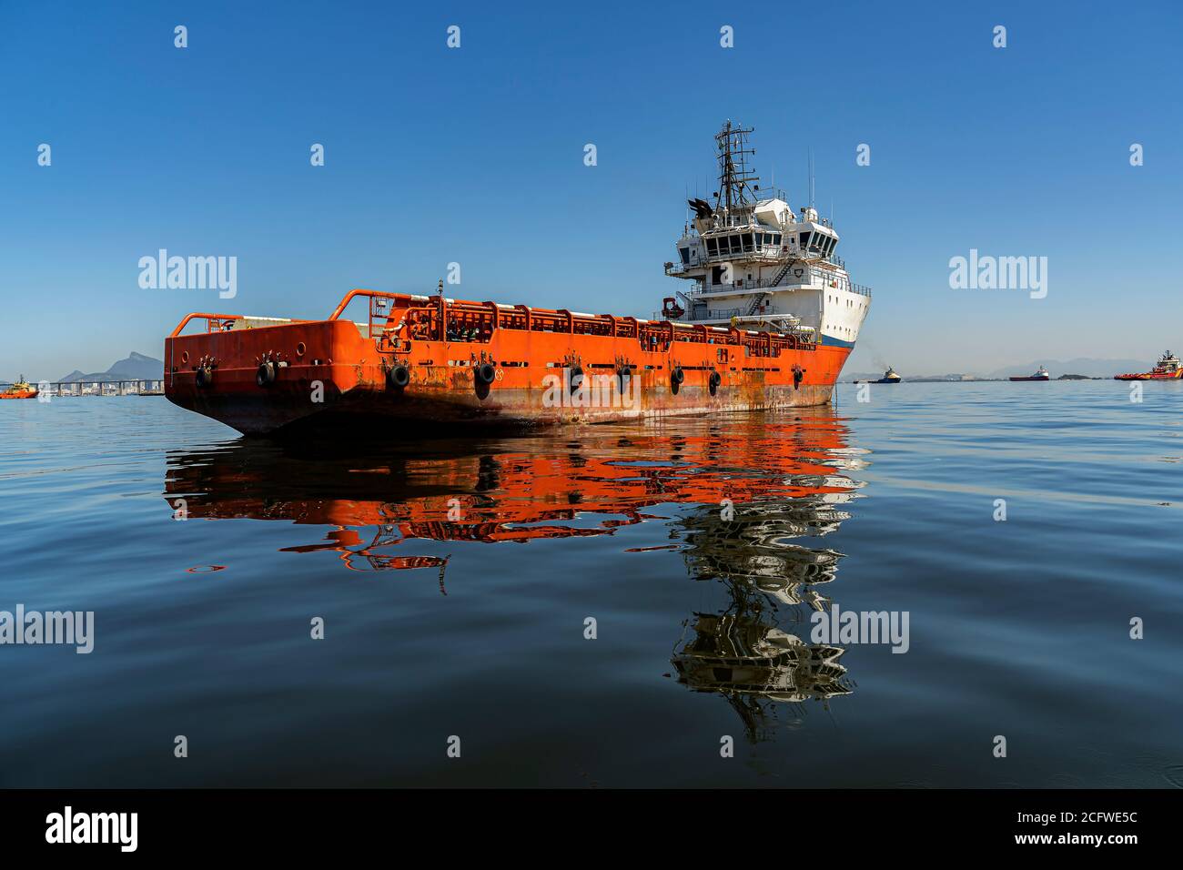 Moored ship. Red boat moored in the calm sea of a bay. Stock Photo