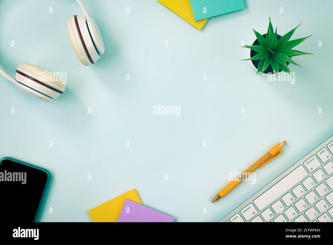 Modern Clean Creative Office Desk or Table on Top View or Flat Lay and Stationery as Keyboard,Headphone,Pen,Sticky Note,Office Plants,Mobile Phone. Mi Stock Photo