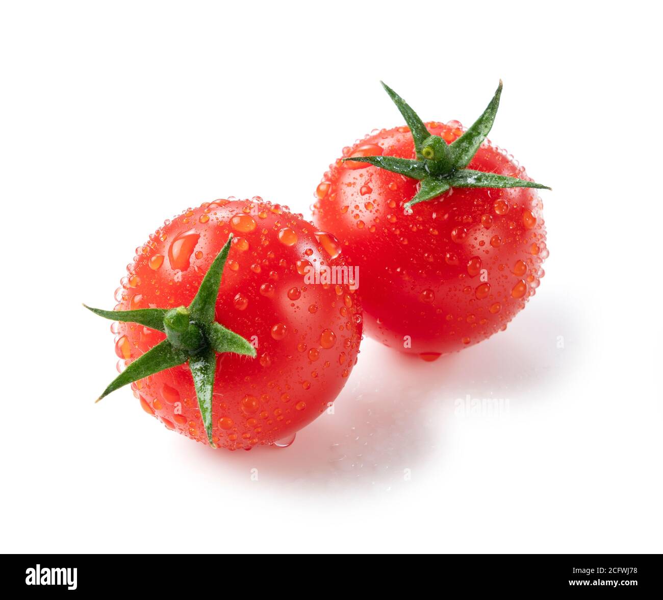 A small tomato with water droplets placed on a white background was ...
