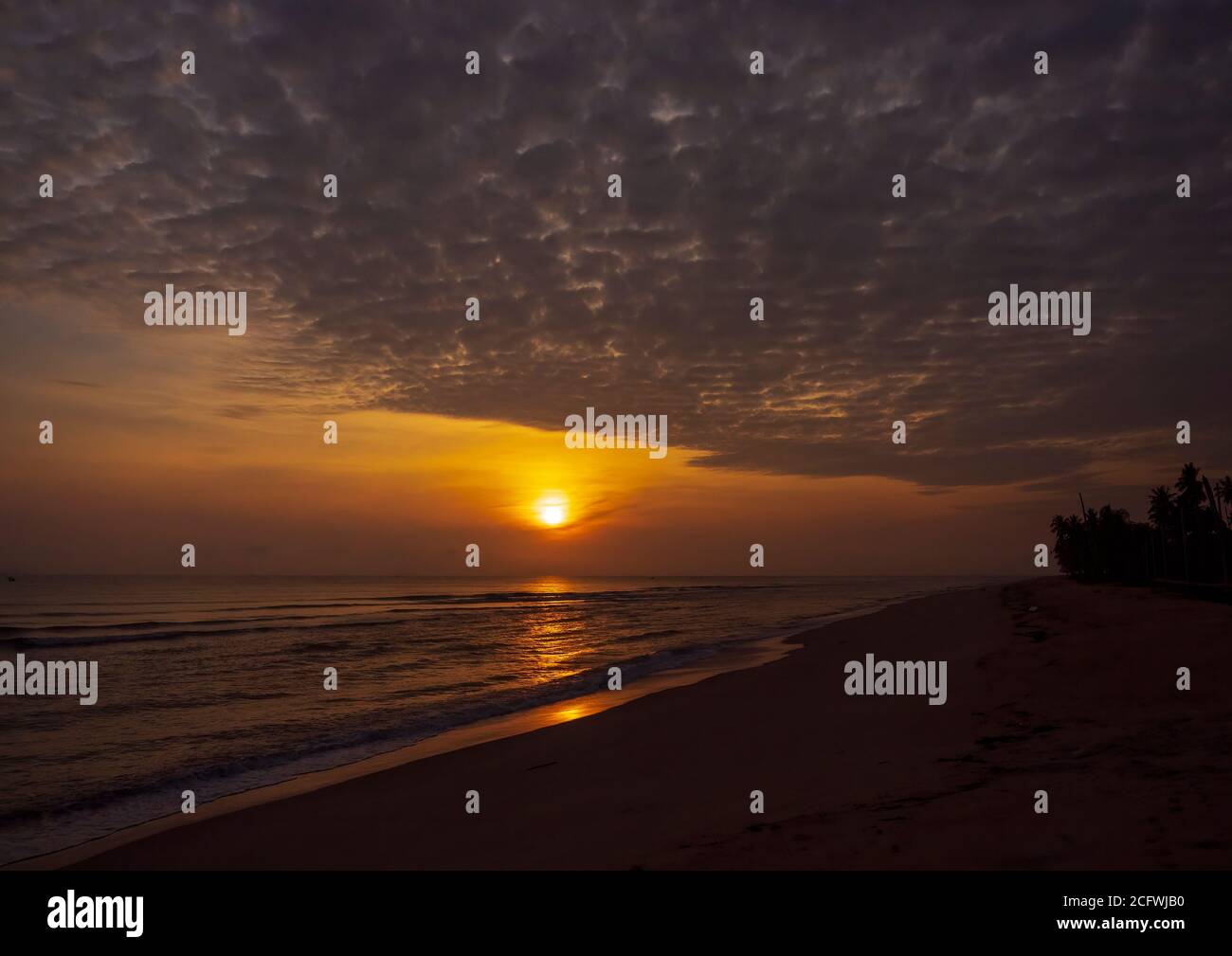 Ocean at dawn with the suns golden orb against the background glow of sunrise. Stock Photo