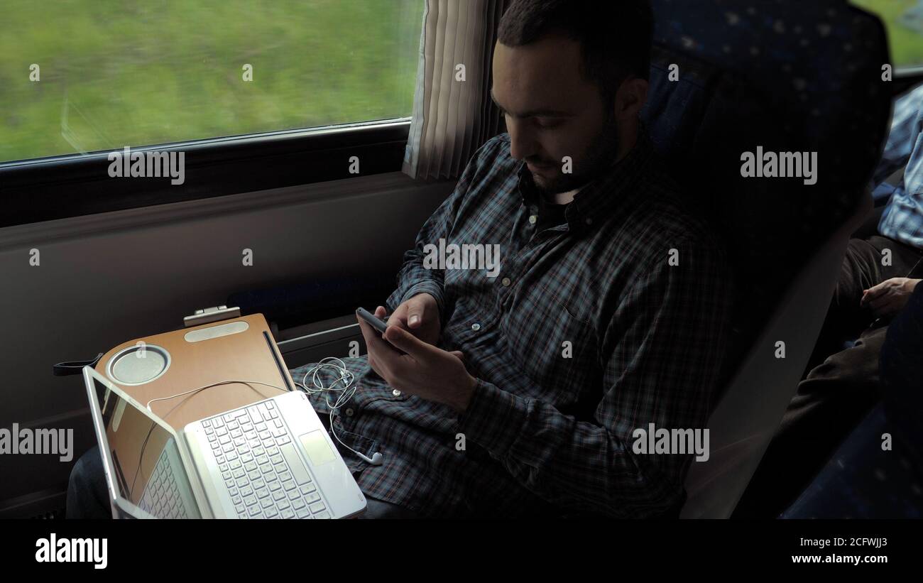 Businessman Commuting To Work On Train Using Mobile Phone. Stock Photo