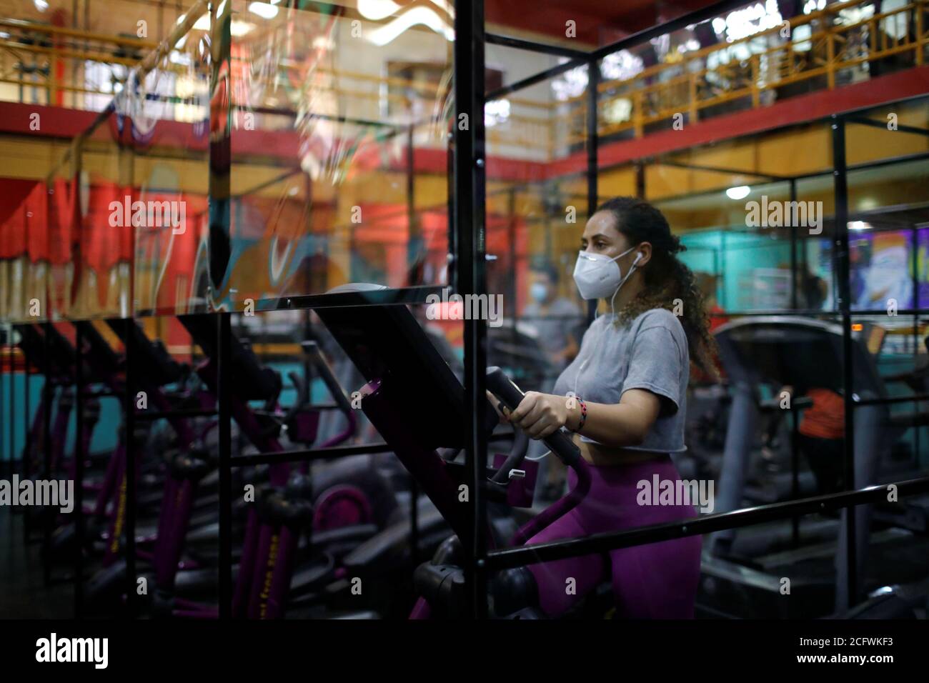 A member exercises on a machine fitted with plastic panels to ensure safe  distance among gym goers, at Bally Sport Center, after a five-month  quarantine, amid the coronavirus disease (COVID-19) pandemic, in