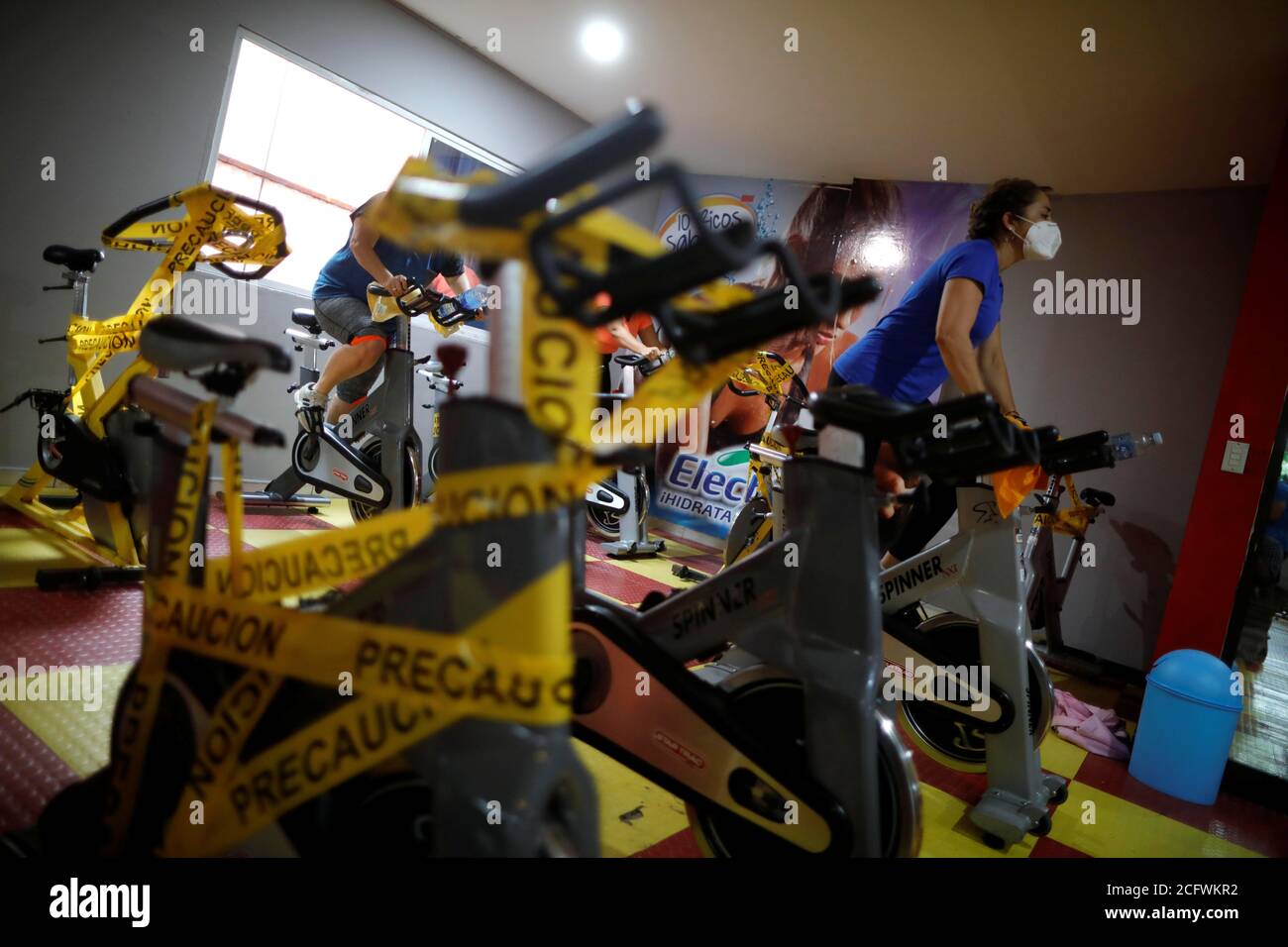 Members use stationary bikes next to machines wrapped in tape to deter  members from using and ensuring safe distance among gym goers, at Bally  Sport Center, after a five-month quarantine, amid the