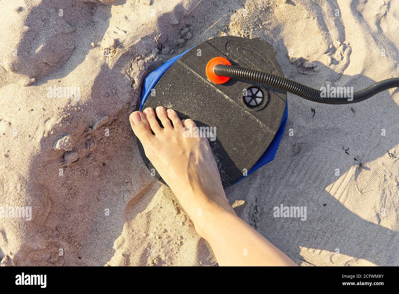 A woman with air foot pump pumps an inflatable mattress or air bed at