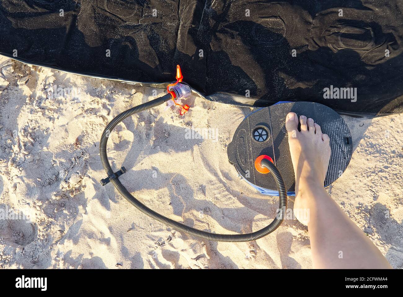 A woman with air foot pump pumps an inflatable mattress or air bed at