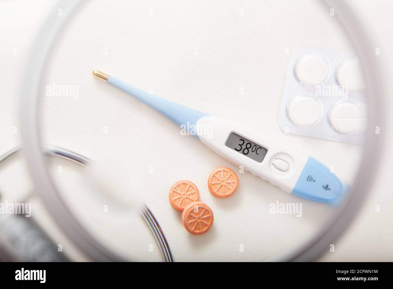 Electronic thermometer with 38 degrees temperature and pills Stock Photo