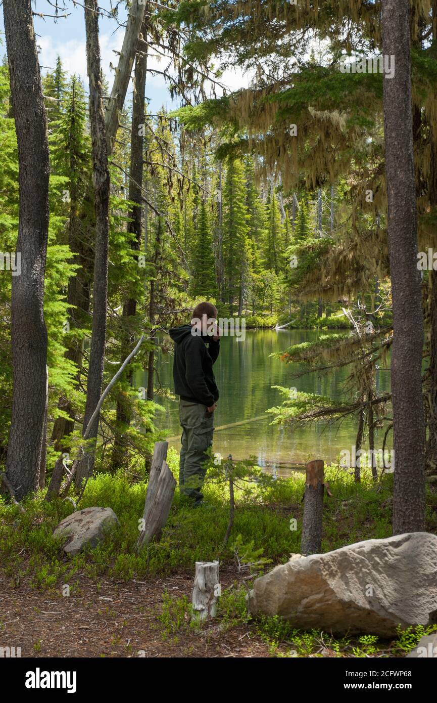 A hiker looks at an unnamed high-elevation lake in the Oregon Cascades.  Near Summit Lake. Stock Photo