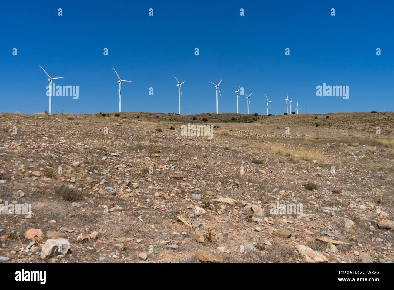 Mountainous landscape with wind energy mills mixing rural life with