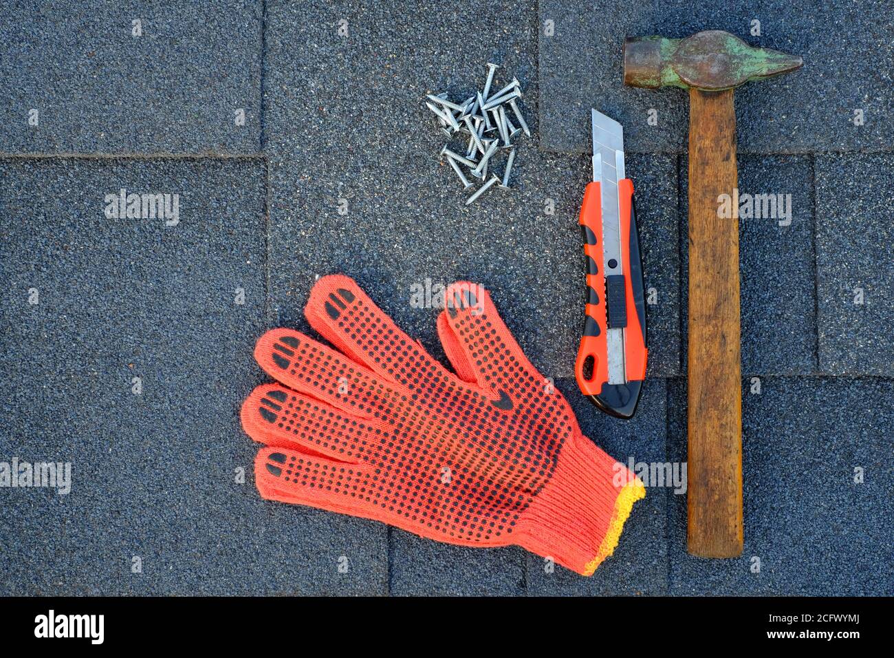 Close up view on bitumen asphalt shingles on a roof with hammer,nails