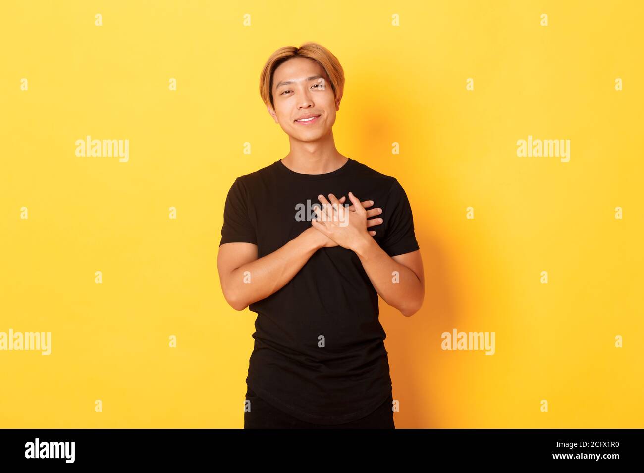 Portrait of touched handsome asian guy holding hands on heart and ...