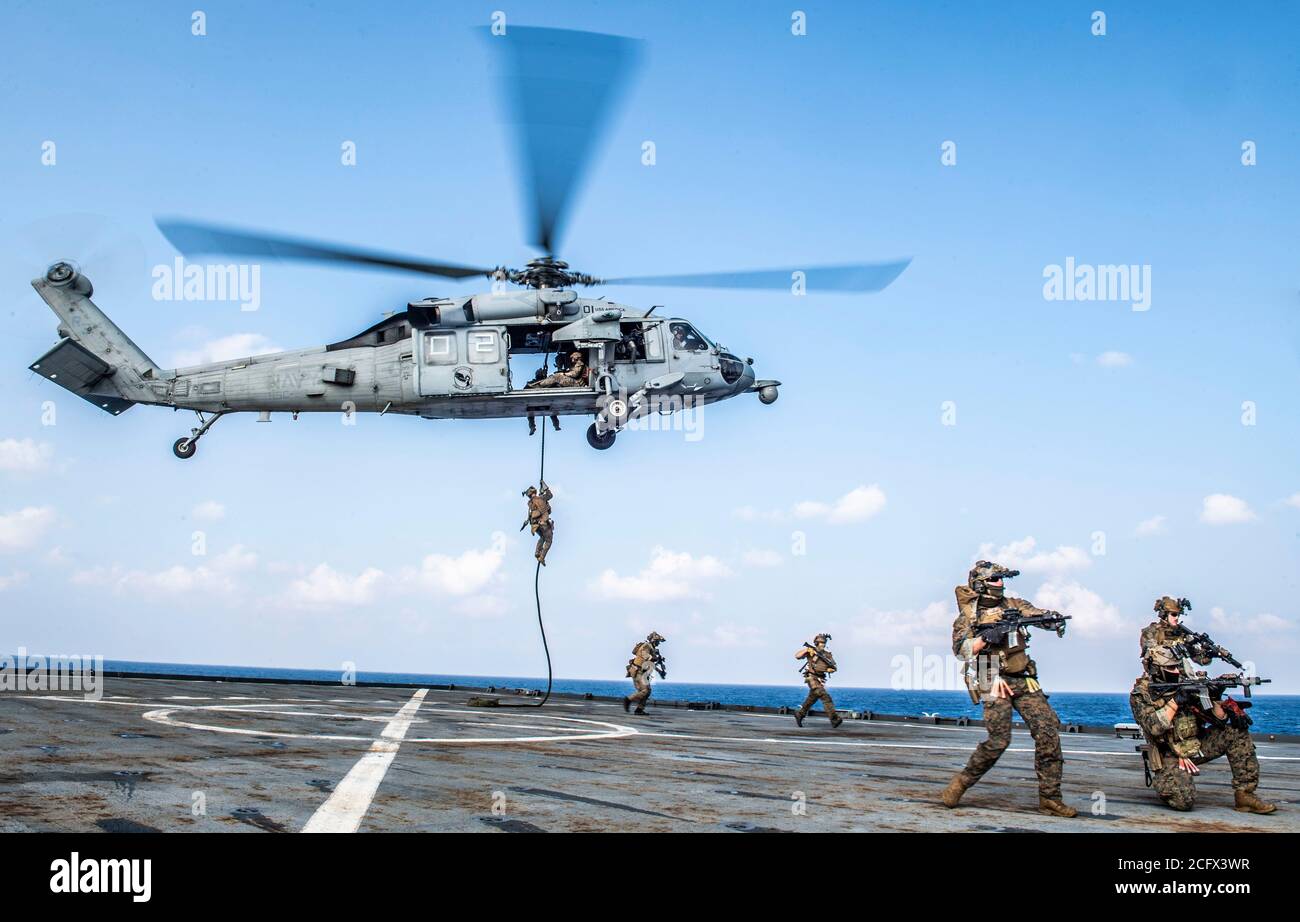 SOUTH CHINA SEA (Sept. 6, 2020) Force Reconnaissance Marines with Command Element, 31st Marine Expeditionary Unit (MEU) fast rope from an MH-60S Seahawk helicopter from the “Archangels” of Helicopter Sea Combat Squadron (HSC) 25, Detachment 6, during a visit, board, search and seizure exercise aboard the amphibious dock landing ship USS Germantown (LSD 42). Germantown, part of the America Amphibious Ready Group assigned to Amphibious Squadron 11, along with the 31st Marine Expeditionary Unit, is operating in the U.S. 7th Fleet area of responsibility to enhance interoperability with allies and Stock Photo
