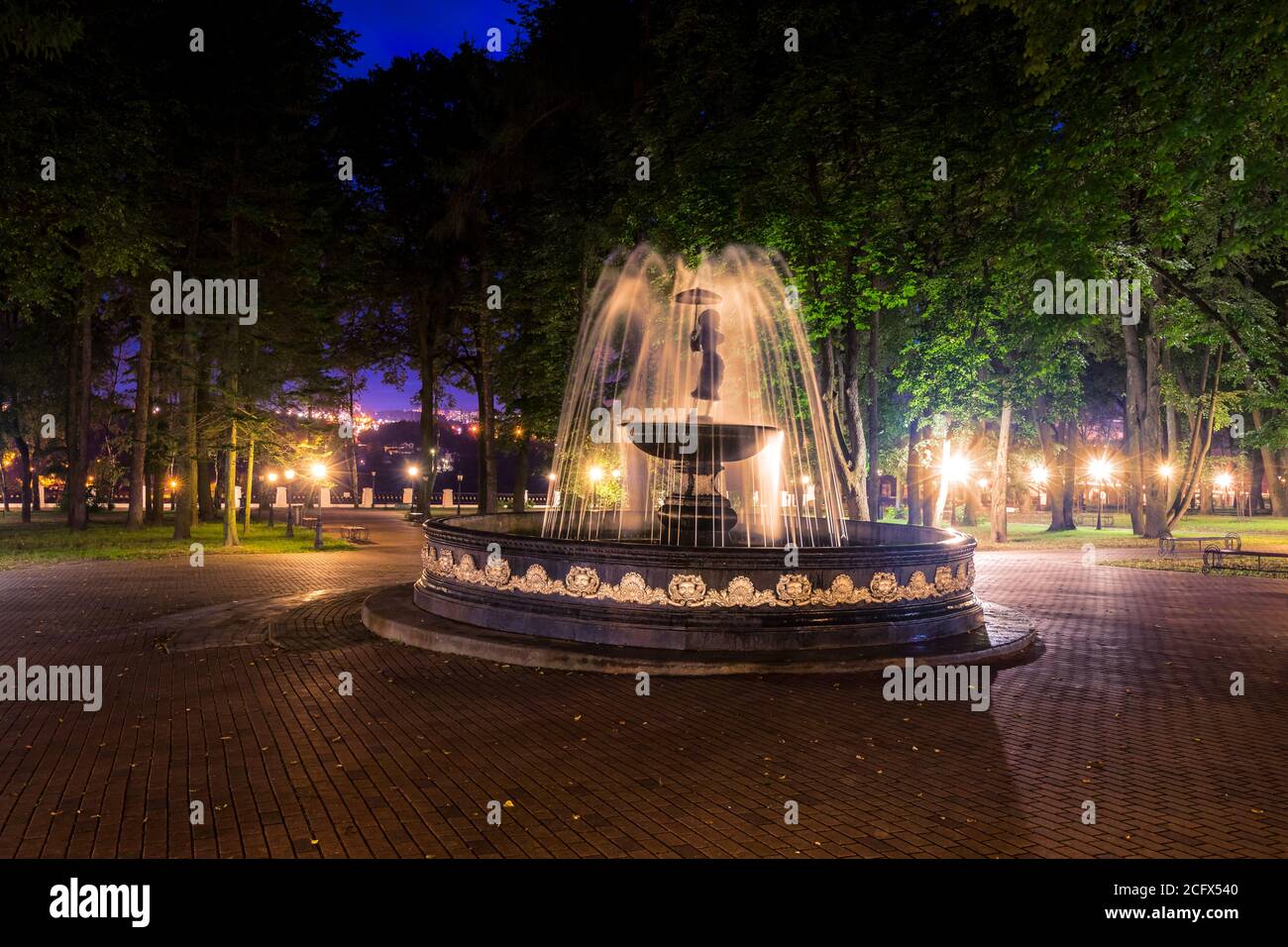 A fountain with blurred streams of water in a night park illuminated by ...