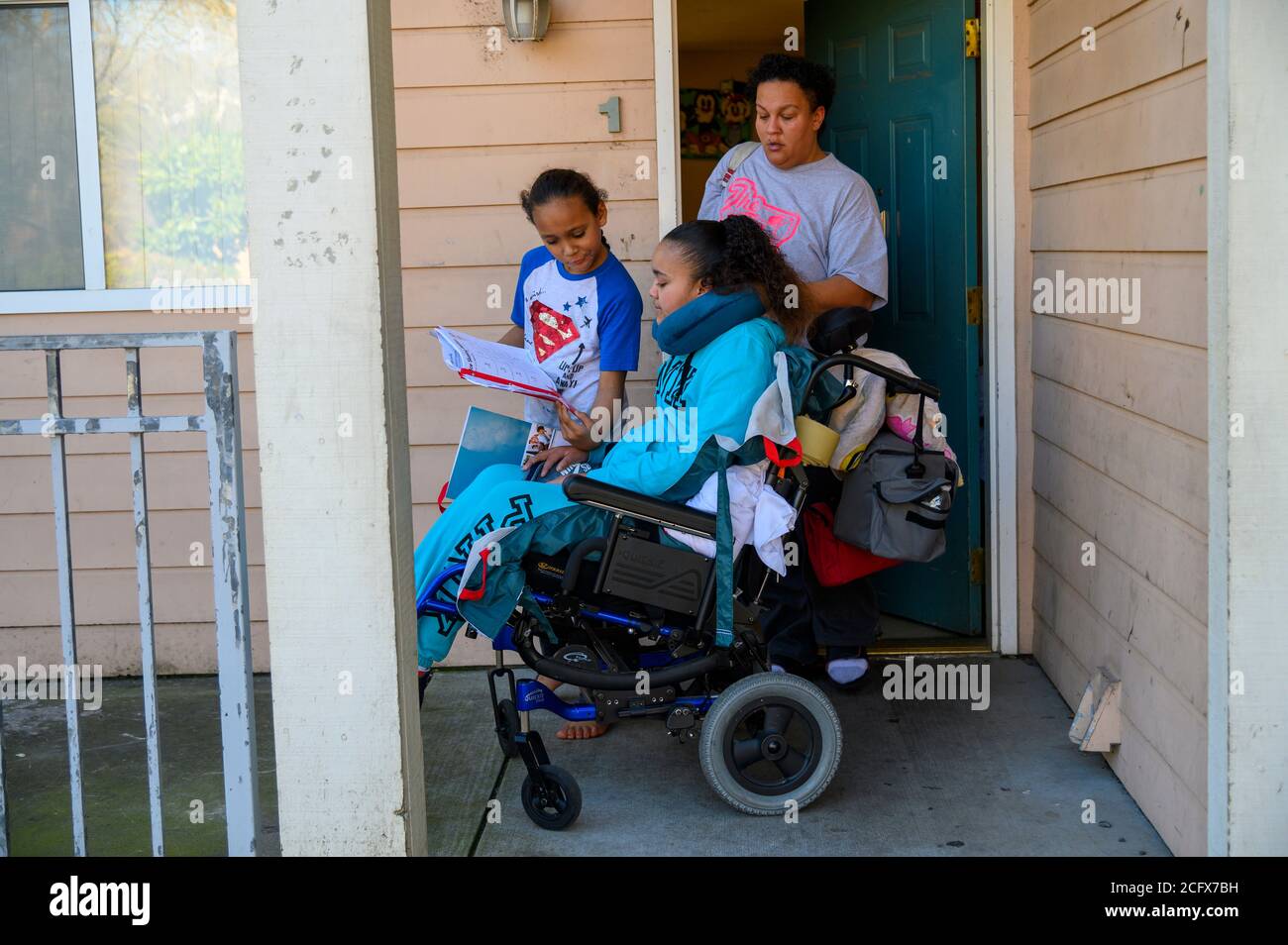 Sacramento, California, USA. 10th Feb, 2020. FELICIA CLARK pushes daughter FELICIA BRENT-VELASQUEZ'S wheelchair to catch the bus to school as her son David shows his homework to his sister. 'We moved her here and been trying to figure out her new way of life. What that means is getting her back into school. All of my children have to go to school, education is key. I want her to do whatever she can with her brain. She's got full brain function. I don't want her to waste it, ' she said. Her daughter died in June 2020 after suffering a stroke and aneurysm. (Credit Image: © Renee C. Byer/Sacram Stock Photo