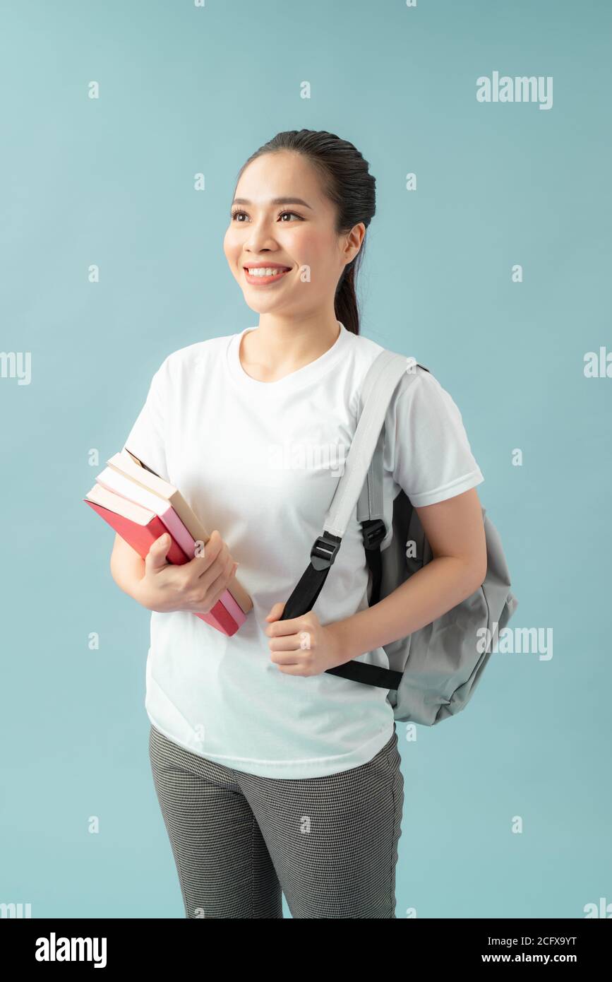 Portrait of a happy friendly girl student with backpack holding books ...