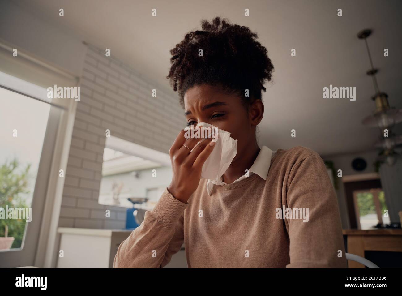Ill sick african american woman blowing running nose got flu caught cold sneezing in tissue - working from home sick Stock Photo