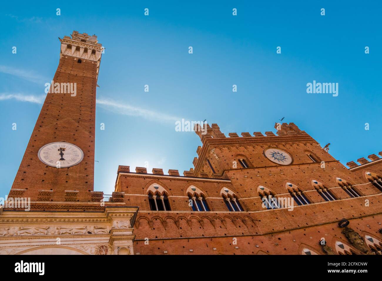 Nice low-angle close-up shot of the medieval town hall Palazzo Pubblico with the bell tower Torre del Mangiaa, in the historic Piazza del Campo on a... Stock Photo