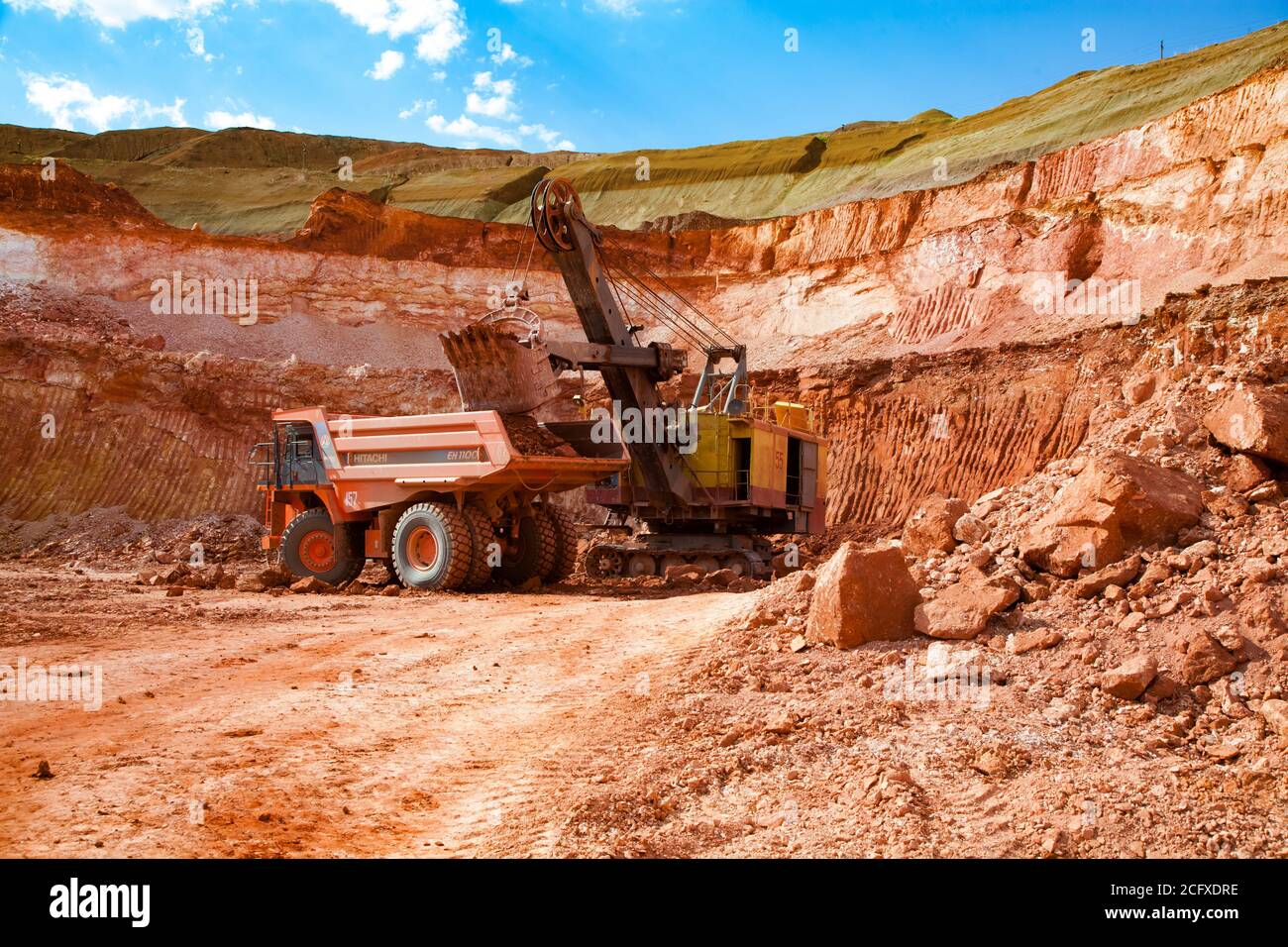 Aluminium ore mining and transporting. Excavator loads bauxite clay to