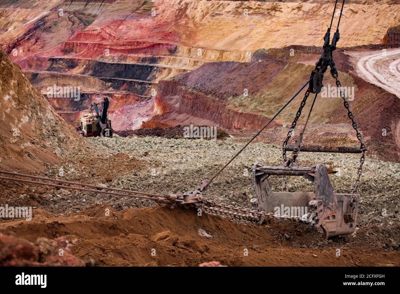 Aluminium ore quarry. Bauxite clay open-cut mining. Grounworks. Walking dragline bucket with empty ground. The multi-color quarry steps and excavator Stock Photo