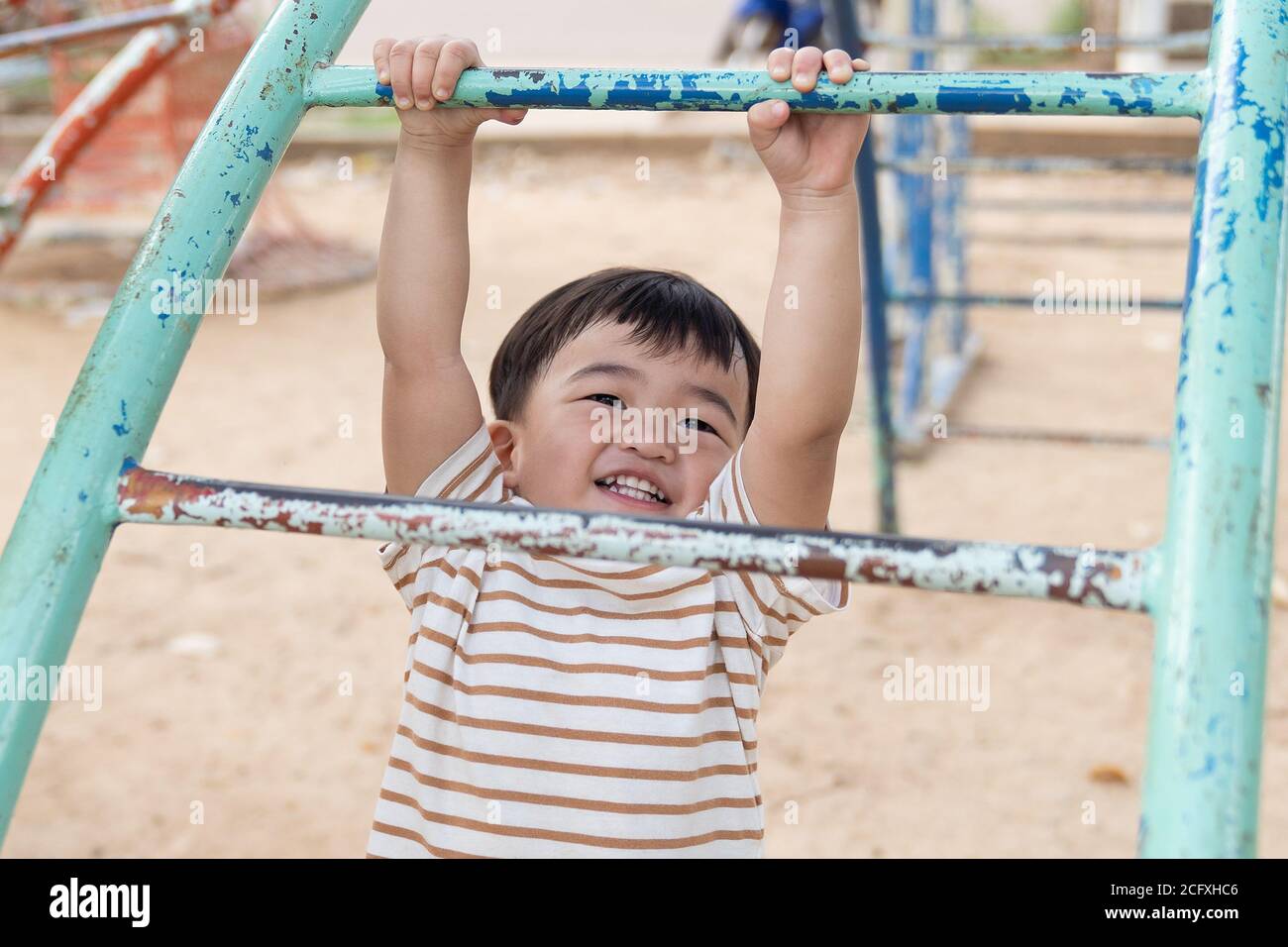 Asian little baby boy enjoy with outdoor zone kid park, climbing steel toy activity on the playground. Stock Photo
