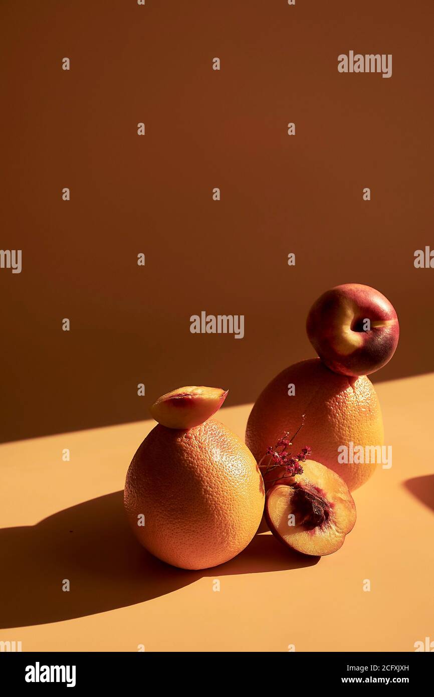 Still life of fruits on an orange background, with shadows and bright