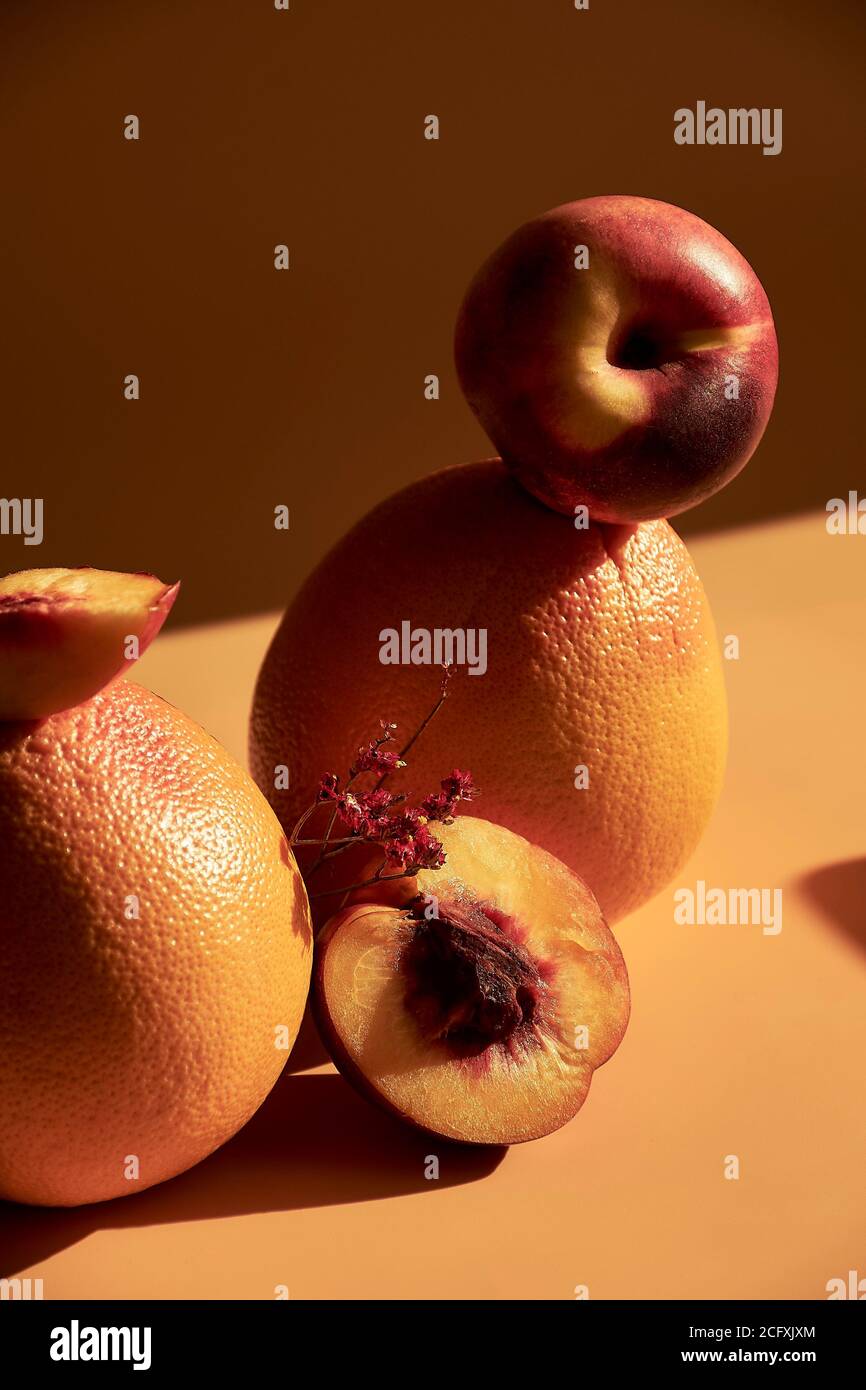 Still life of fruits on an orange background, with shadows and bright