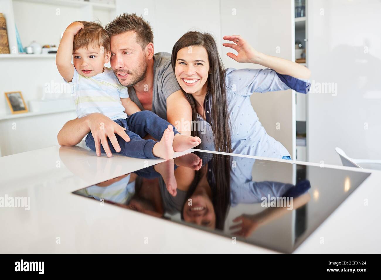 Happy small family with parents and toddler at home in the kitchen Stock Photo