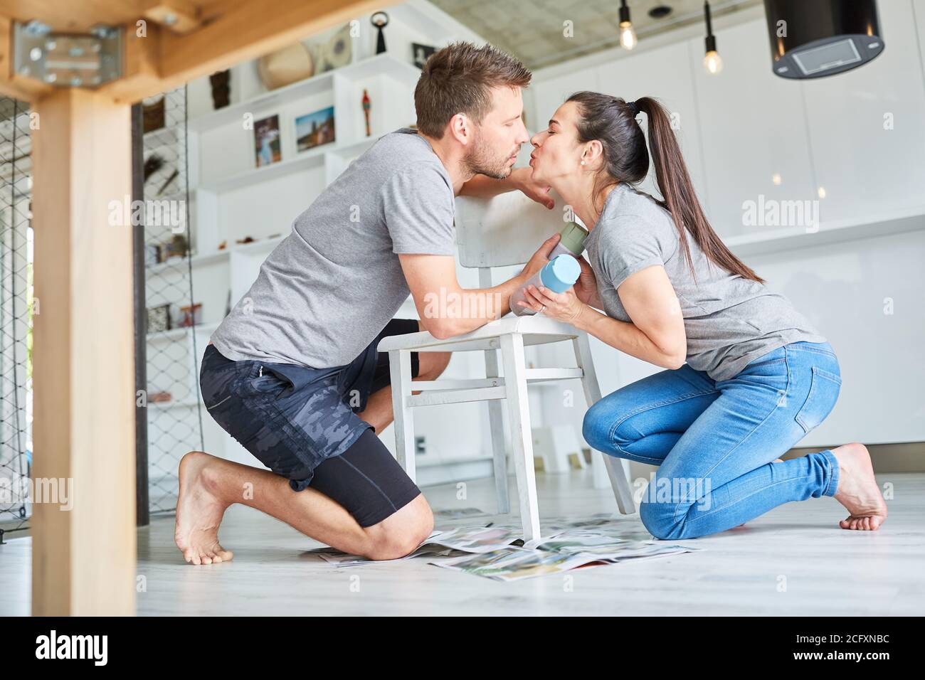 Young handyman couple kissing while refurbishing furniture and painting chair Stock Photo