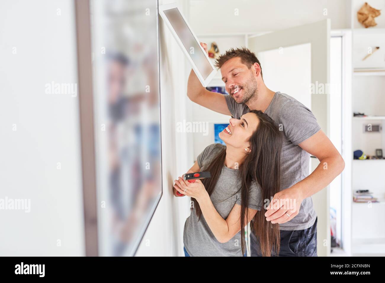 Handyman couple fasten a picture frame to the wall with hammer and nail Stock Photo