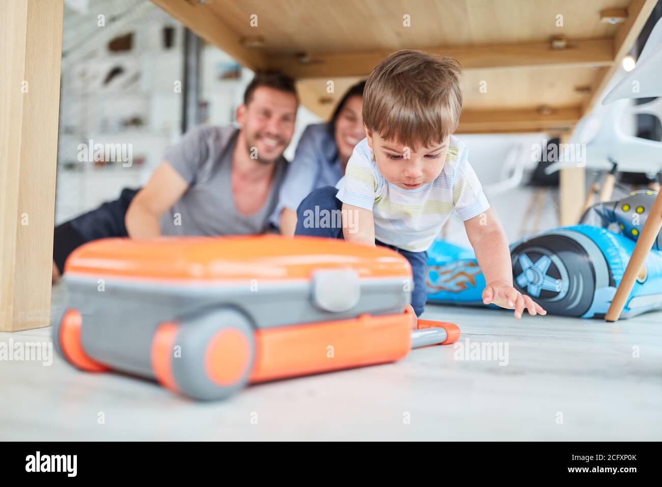 Child with a suitcase plays travel in the living room on the floor