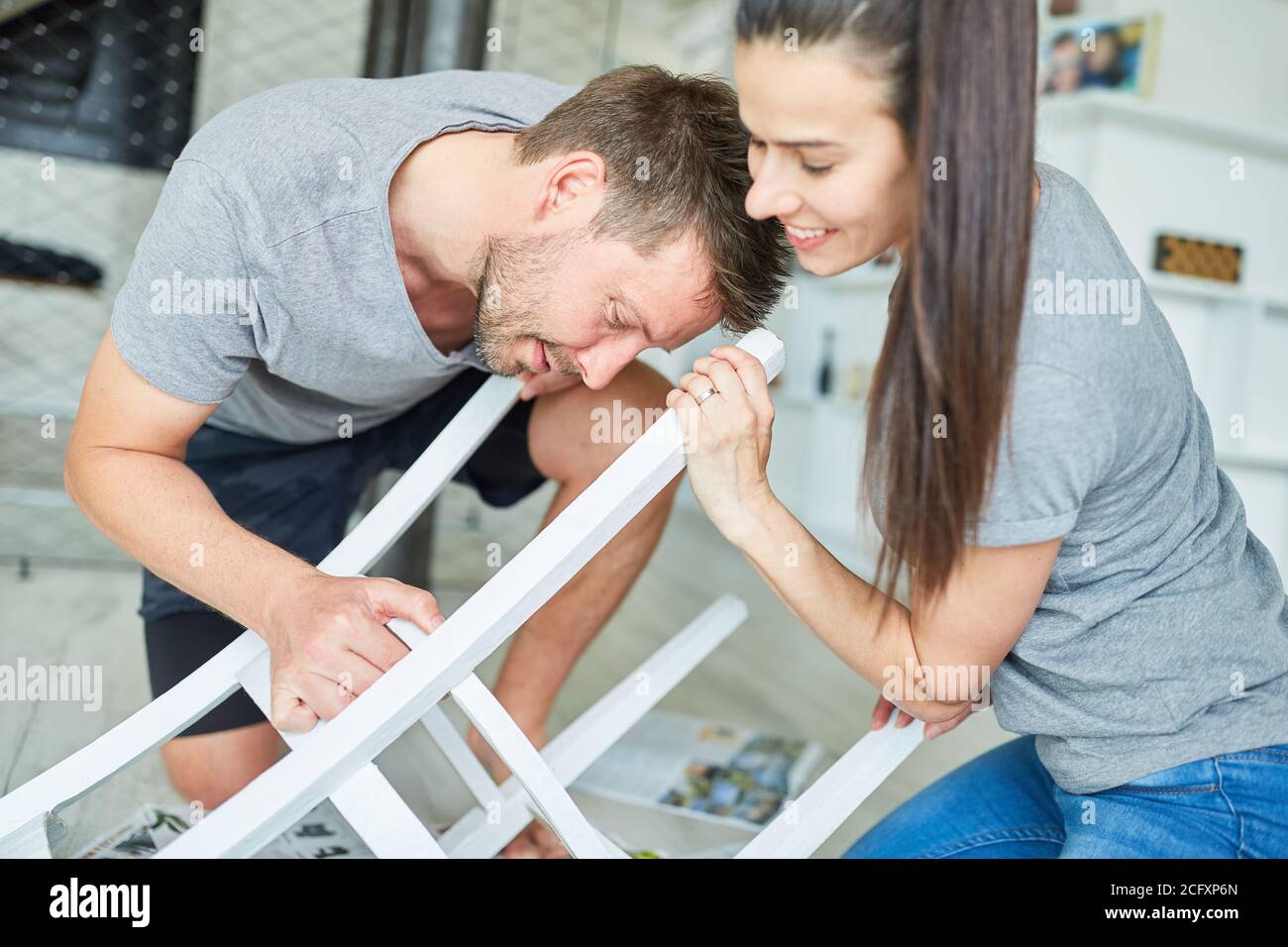 Young couple as do-it-yourselfers to refurbish and paint a chair as upcycling Stock Photo