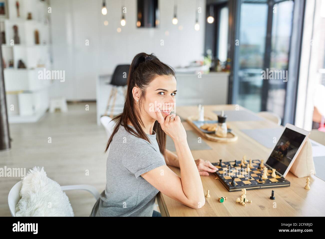 Thoughtful young woman video chat playing chess on laptop computer at home Stock Photo
