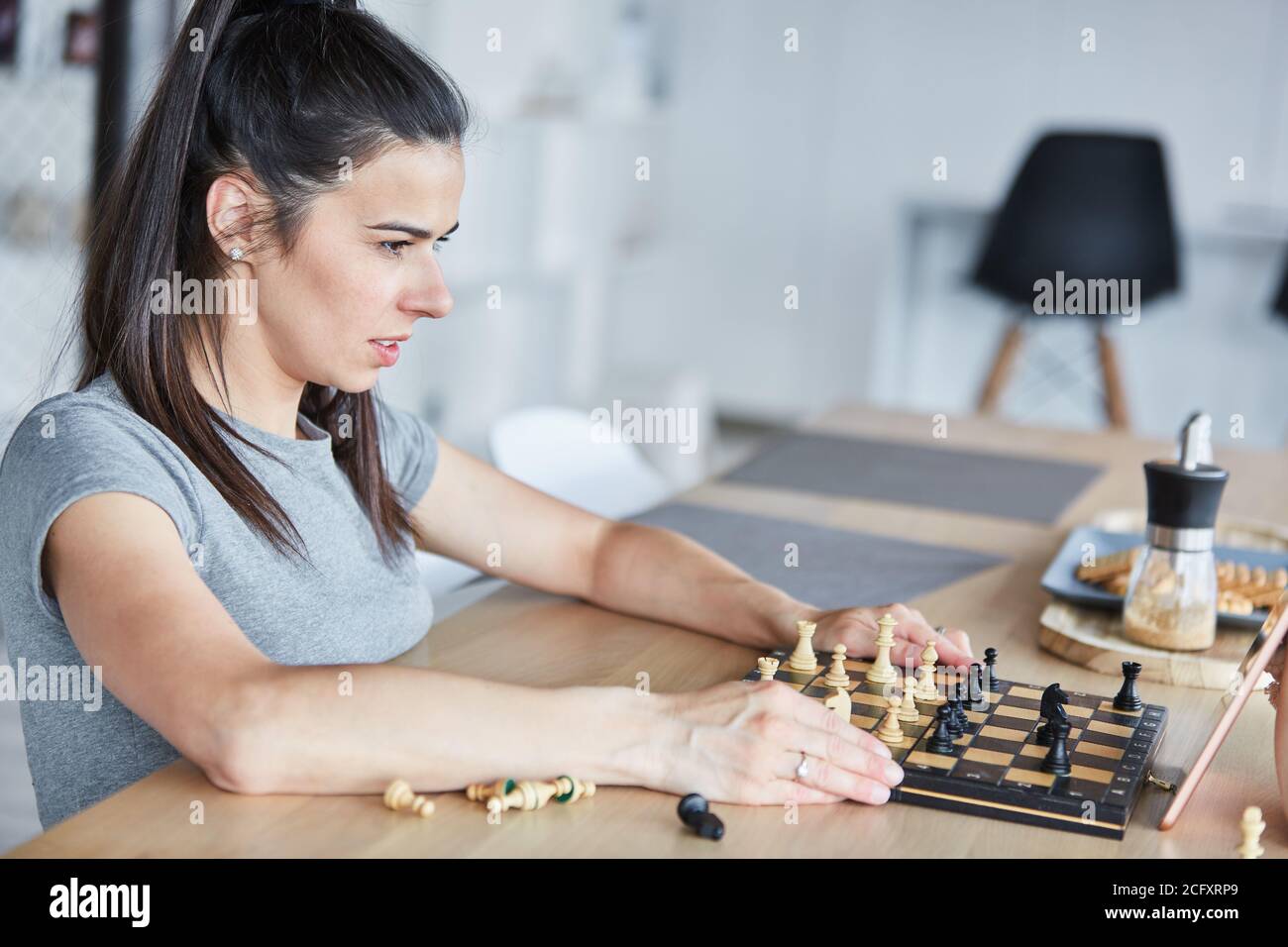 Woman thinking about a problem playing chess in video chat online Stock Photo