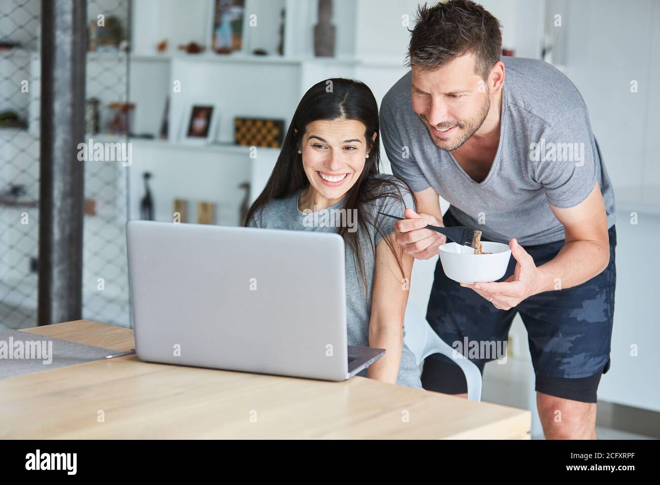 Couple watching tutorial on hair coloring themselves on laptop computer in the living room at home Stock Photo