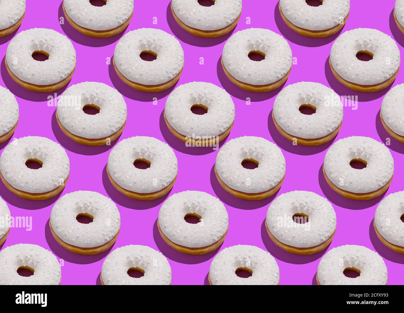 Delicious donuts with white sugary icing and sprinkles over neon purple background Stock Photo
