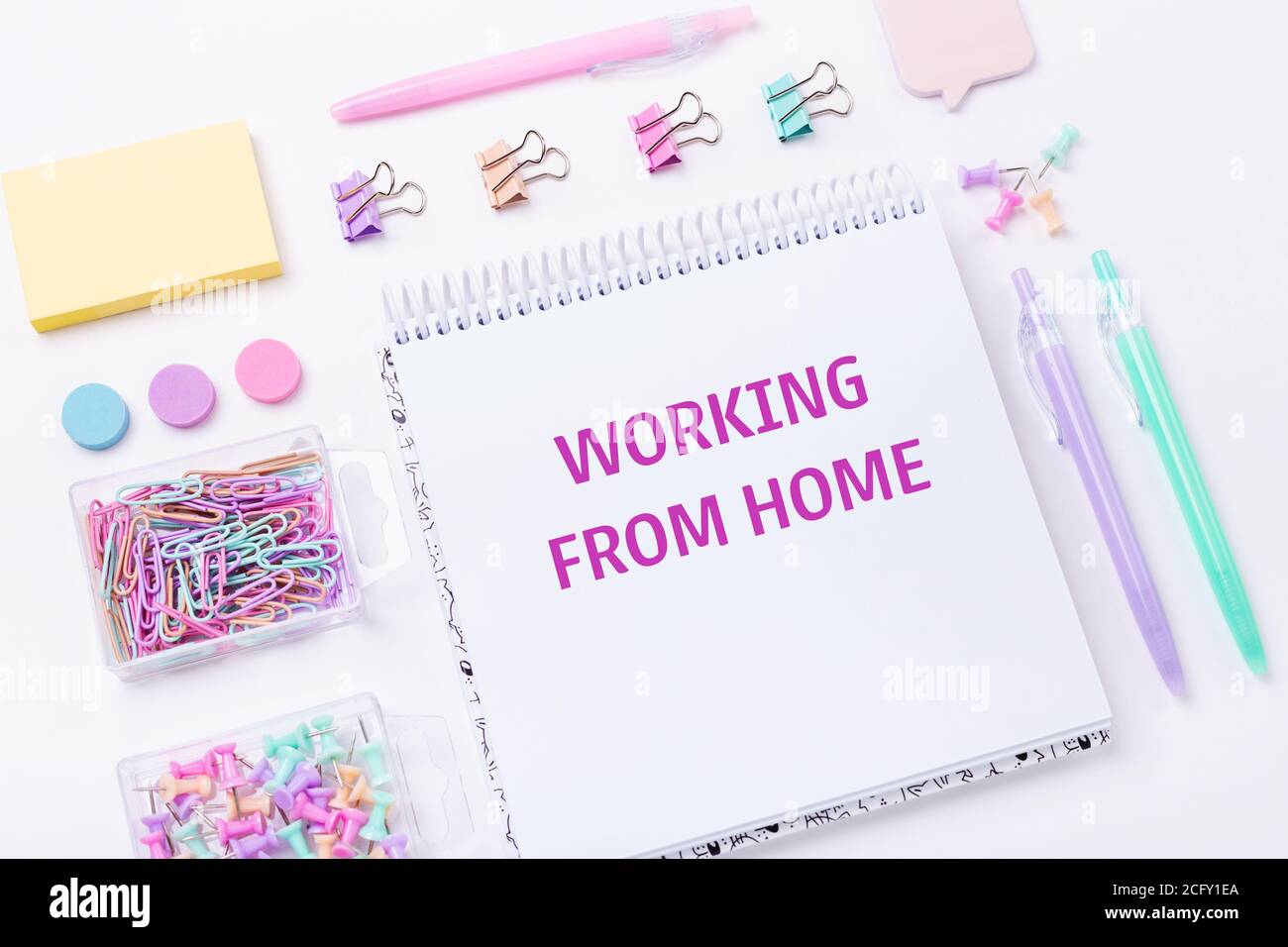 Home office workplace with notebook and pastel colorful study accessories on pink background. Working from home concept. Top view - Image Stock Photo