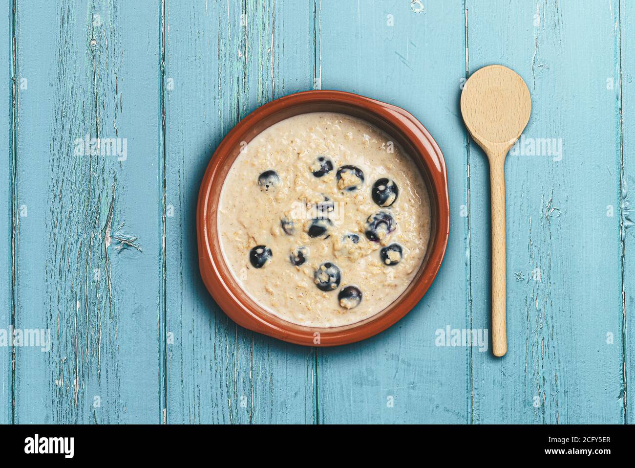 above view of healthy oatmeal or porridge with blueberries in bowl rustic blue wooden table Stock Photo