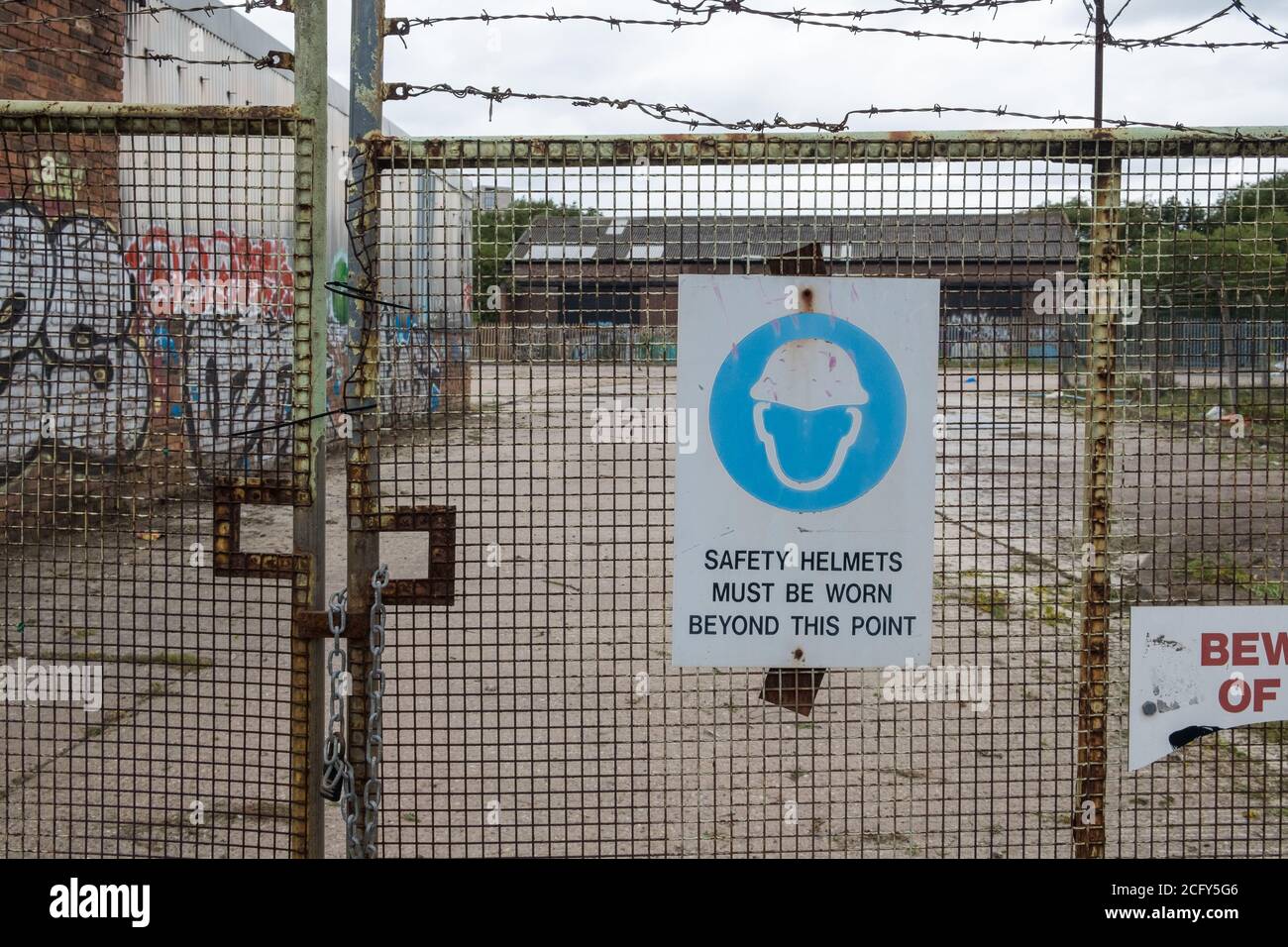 Sign on wire fence at construction site saying: Safety Helmets Must Be Worn Beyond This Point Stock Photo