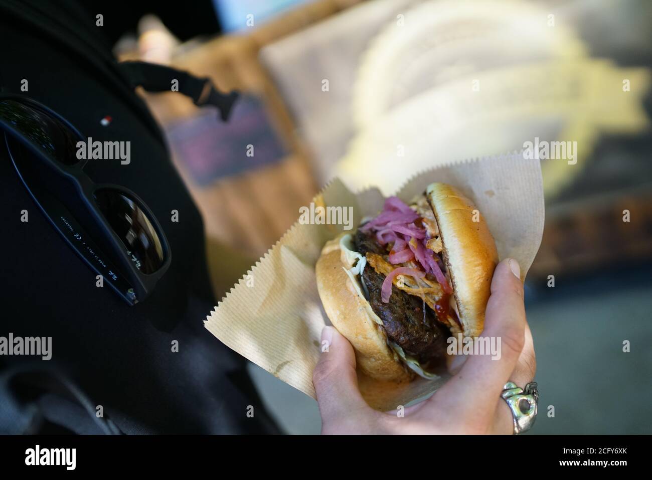 Burger in hand with red and white onions at a foodfestival Stock Photo