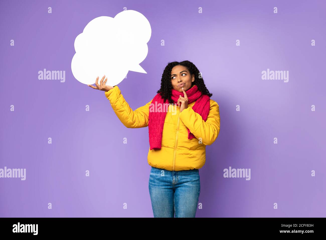 Thoughtful Black Girl Holding Speech Bubble Above Head In Studio Stock Photo